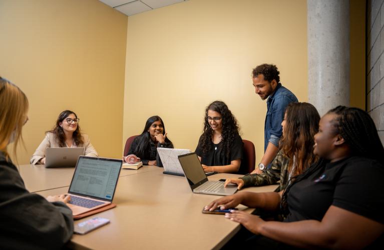 seven students gather around a table in a group study room