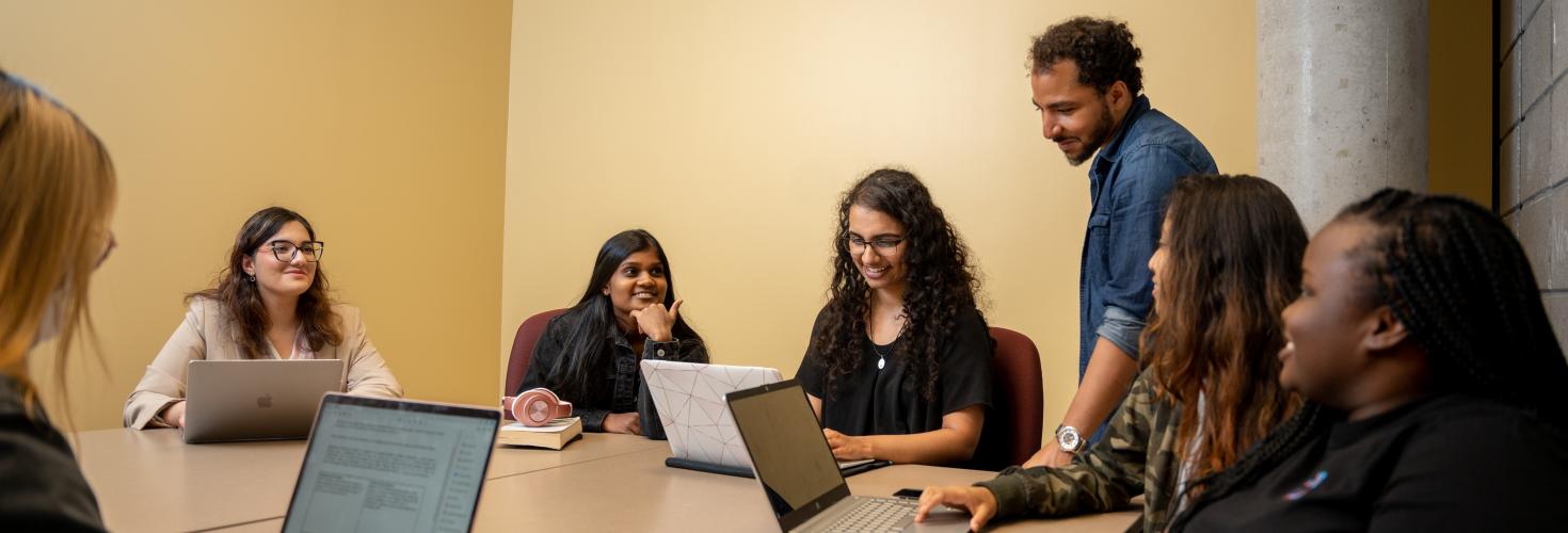 seven students gather around a table in a group study room